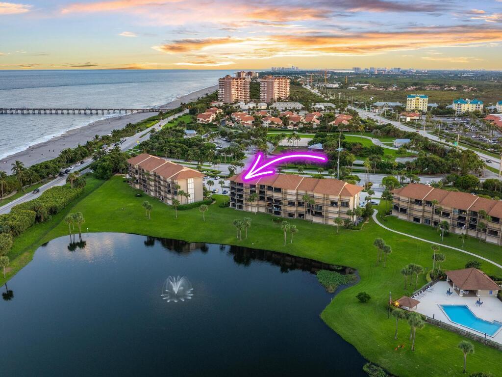 An aerial view shows multi-story residential buildings near a lake, a beach, and a pier — 601 S Seas Drive # 106, Jupiter FL 33477, JUPITER, FL