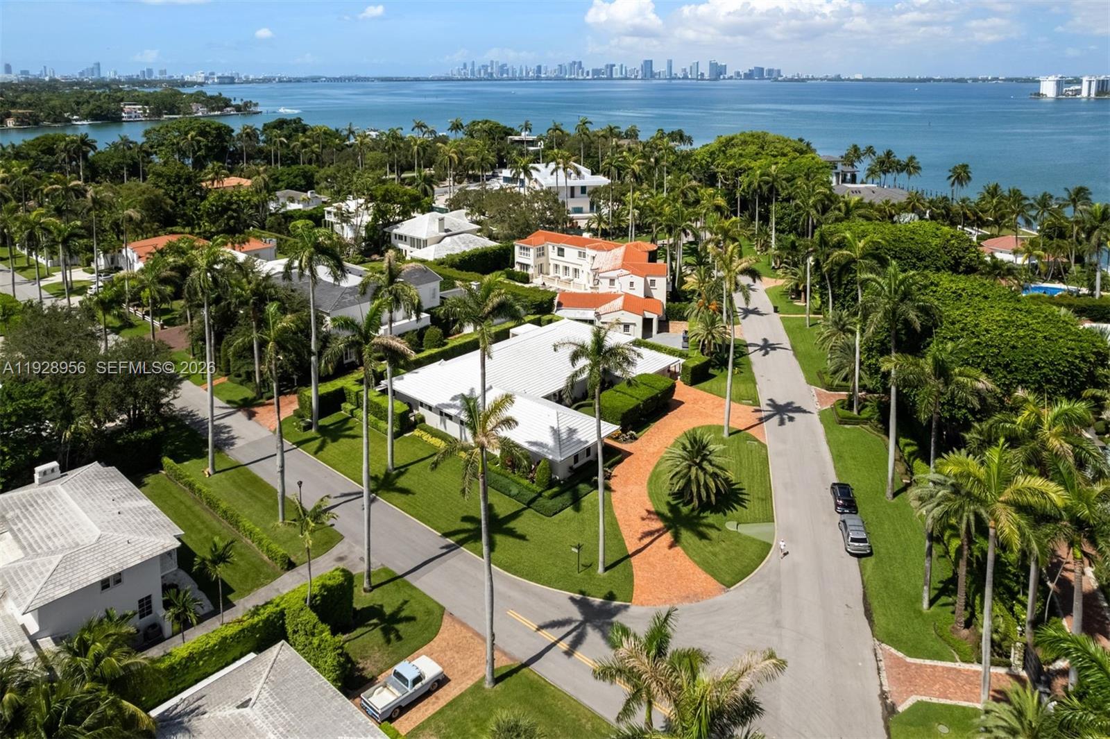 An aerial view shows a residential neighborhood with palm trees, houses, and a coastal bay — 55 La Gorce Cir, Miami Beach FL 33141, MIAMI BEACH, FL