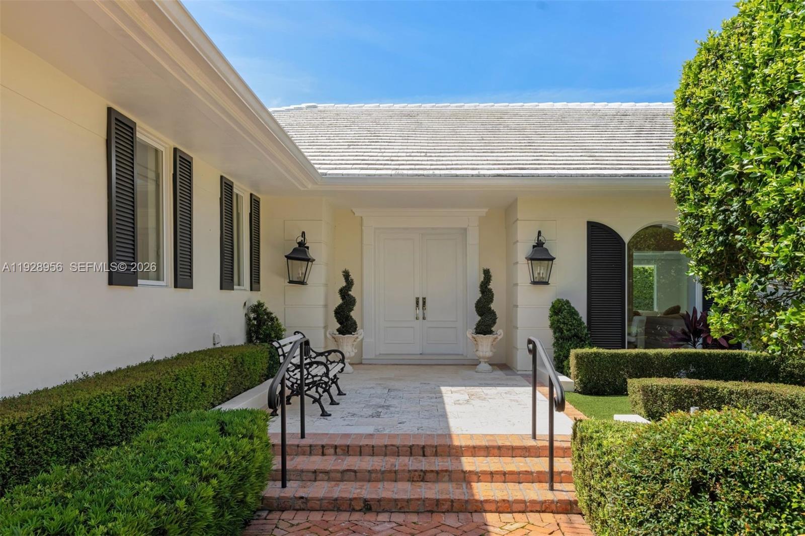 The exterior of a house features a white double door entrance with brick steps — 55 La Gorce Cir, Miami Beach FL 33141, MIAMI BEACH, FL