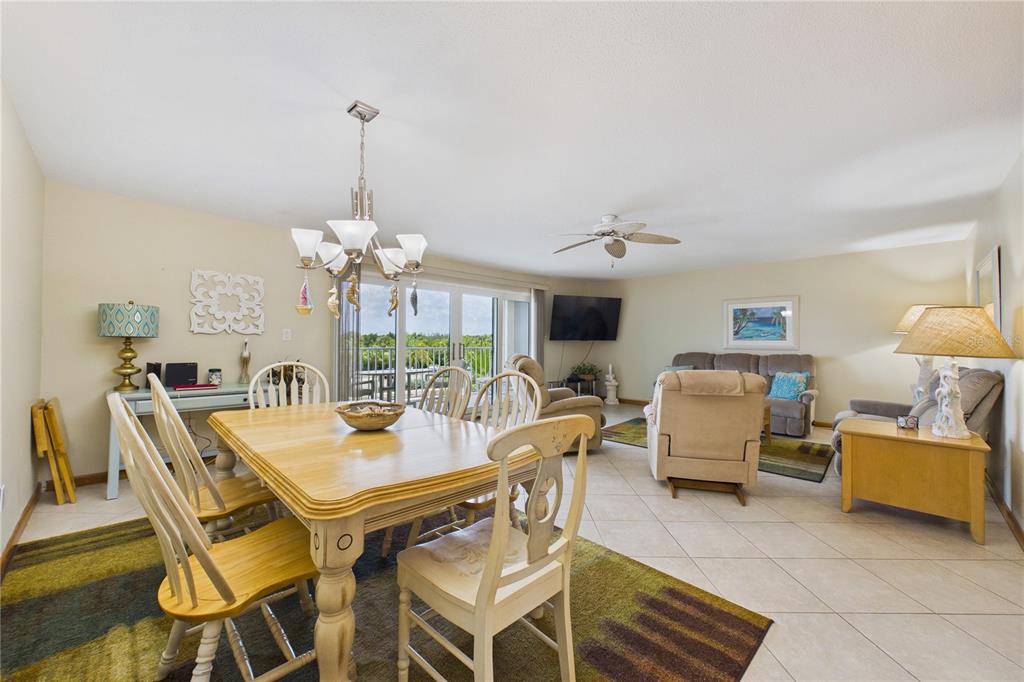 A dining area and living room with tile floors, a ceiling fan, and balcony access — 19610 GULF BOULEVARD UNIT 206, INDIAN ROCKS BEACH, FL