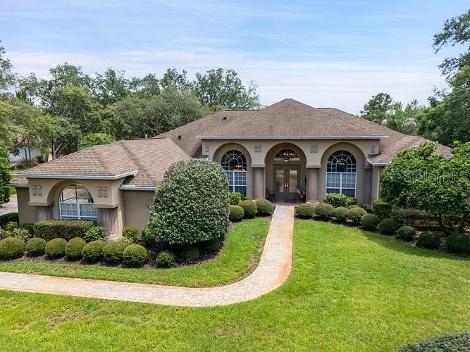 A single-story house with a tan exterior, arched windows, and a paved walkway — 10470 RAMBLE RIDGE COURT, WEEKI WACHEE, FL