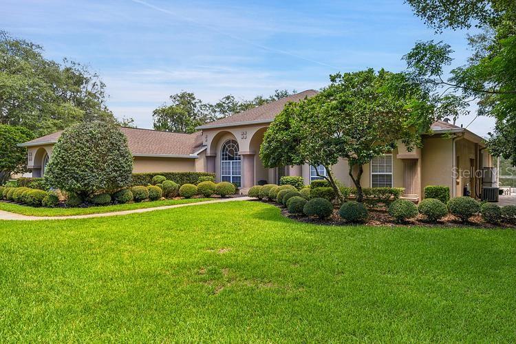 A single-story house with a tan exterior, arched windows, and a manicured lawn — 10470 RAMBLE RIDGE COURT, WEEKI WACHEE, FL