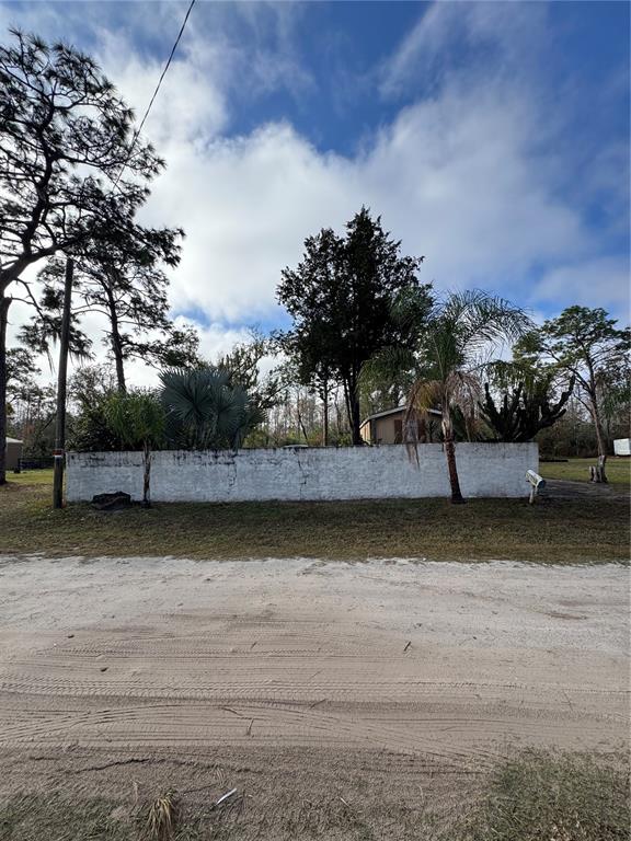 A white masonry wall stands in front of a house surrounded by trees and palms — 12748 VIA PLAZA WAY, NEW PORT RICHEY, FL