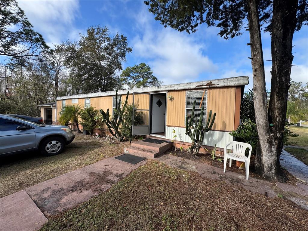 A single-story mobile home with tan siding, a front entrance, and cacti in the yard — 12748 VIA PLAZA WAY, NEW PORT RICHEY, FL