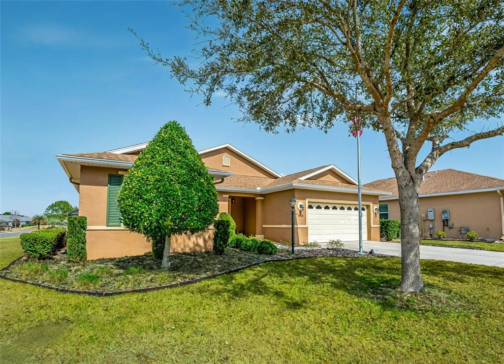 A tan single-story house with a two-car garage and a large tree in the front yard — 9222 SW 97TH CIRCLE, OCALA, FL