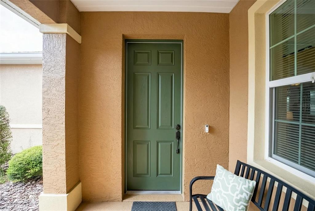 A green front door is set into a tan stucco wall next to a window — 9222 SW 97TH CIRCLE, OCALA, FL