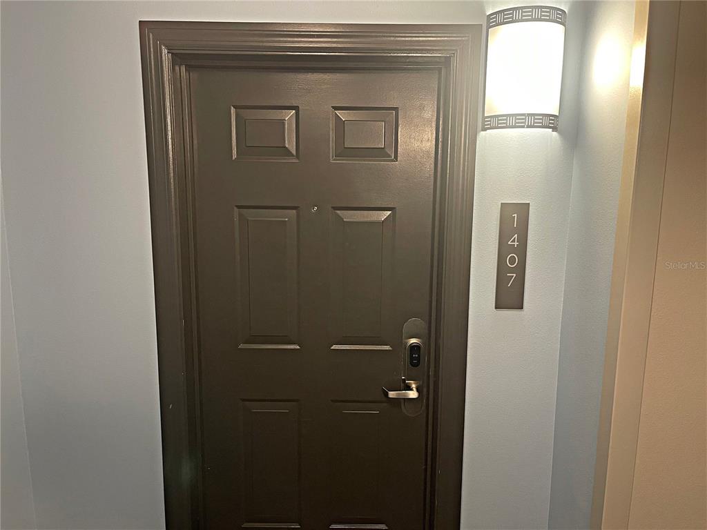 A dark brown door with a digital lock and a vertical unit number sign — 14501 GROVE RESORT AVENUE UNIT 1407, WINTER GARDEN, FL