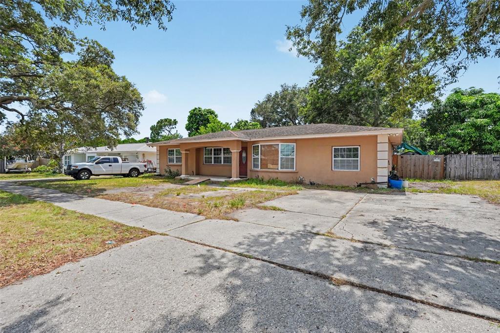 A single-story tan house with a concrete driveway and a large front yard — 1358 S KEENE ROAD, CLEARWATER, FL