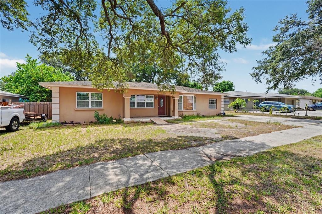 A single-story tan house with a front porch and a large tree in the yard — 1358 S KEENE ROAD, CLEARWATER, FL