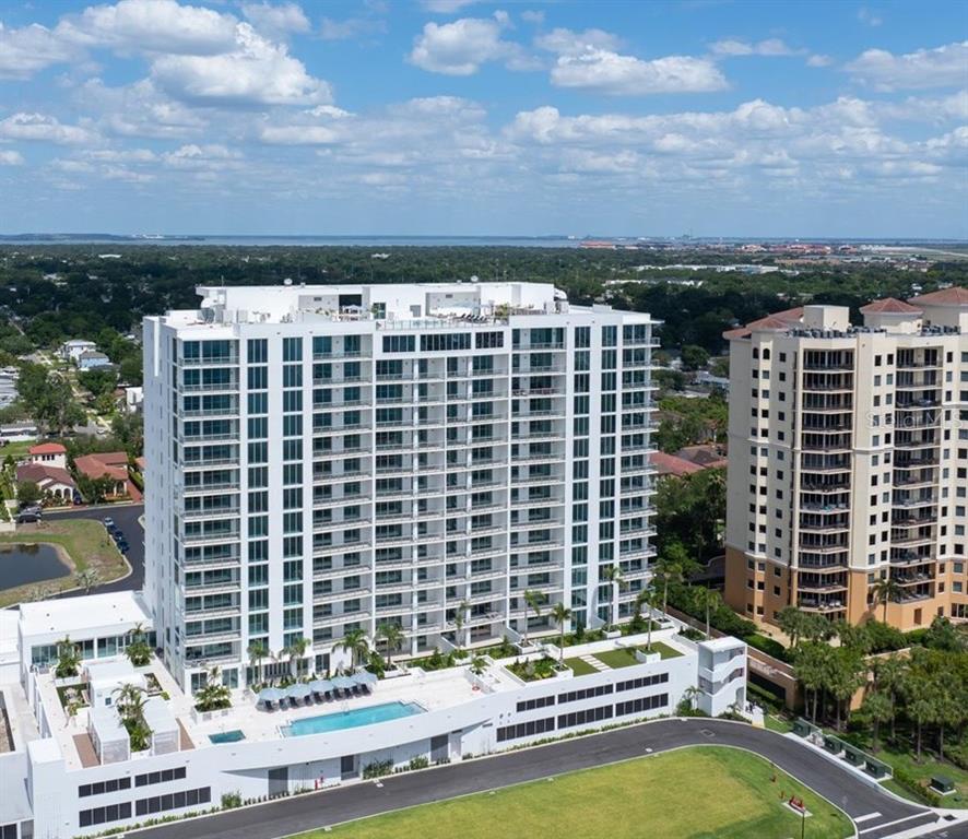 A modern kitchen features white upper cabinets, light wood lower cabinets, and a central island — 5713 BOWEN DANIEL DRIVE UNIT 604, TAMPA, FL