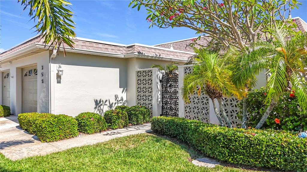 A single-story house exterior features a garage, a decorative privacy screen, and manicured landscaping — 355 BOCA CIEGA POINT BOULEVARD UNIT 355, ST PETERSBURG, FL