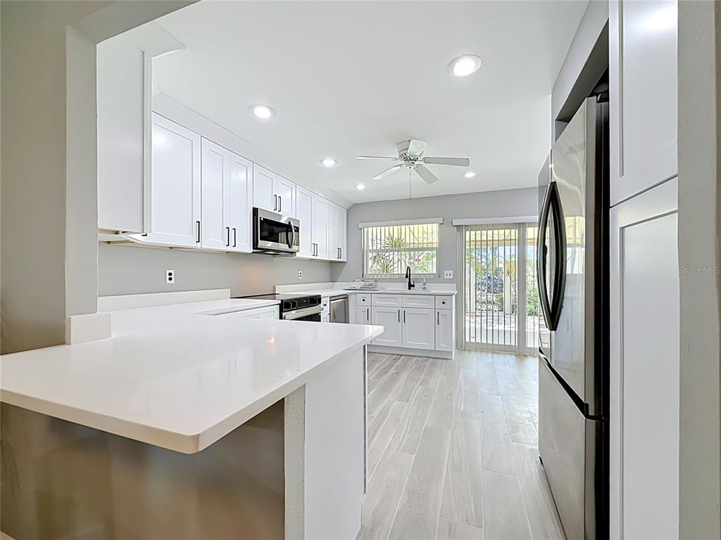 A bright kitchen features white cabinetry, stainless steel appliances, and light-colored wood-look tile flooring — 355 BOCA CIEGA POINT BOULEVARD UNIT 355, ST PETERSBURG, FL