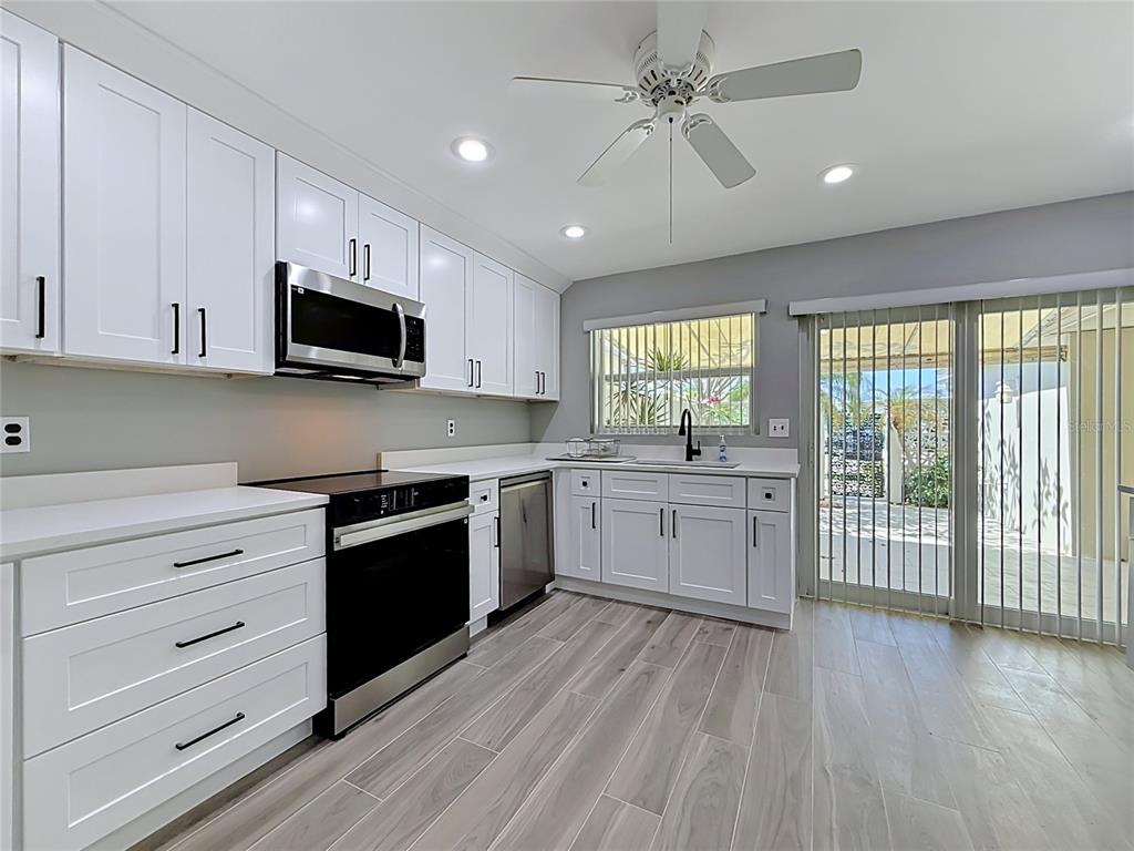 A kitchen with white cabinets, stainless steel appliances, and light wood-look tile flooring — 355 BOCA CIEGA POINT BOULEVARD UNIT 355, ST PETERSBURG, FL