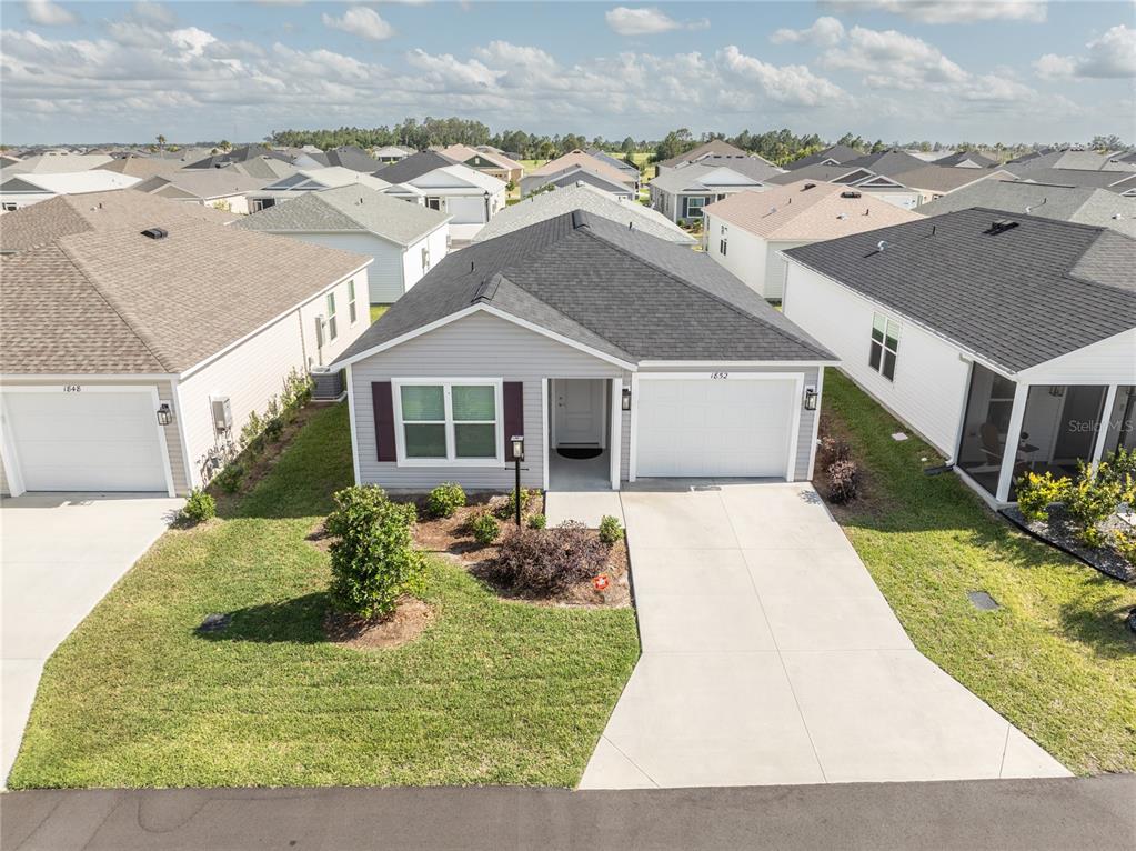 A single-story suburban house with a gray facade, dark roof, and a concrete driveway — 1852 TIMON STREET, THE VILLAGES, FL