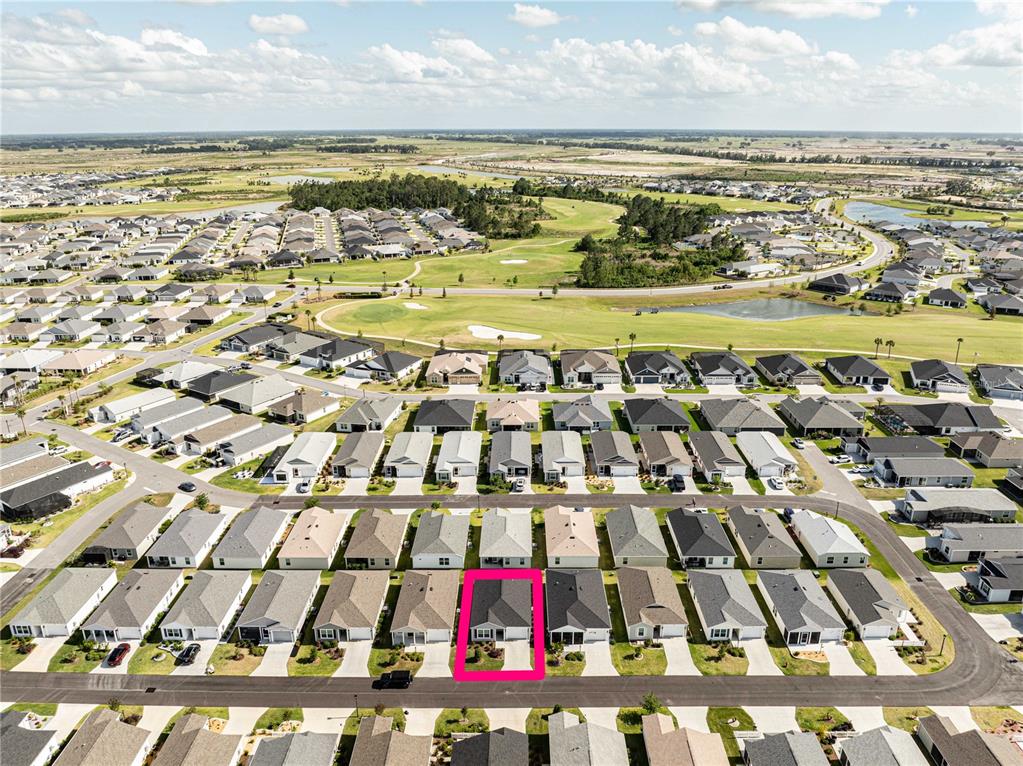 An aerial view shows a residential neighborhood with a single house highlighted in a pink box — 1852 TIMON STREET, THE VILLAGES, FL