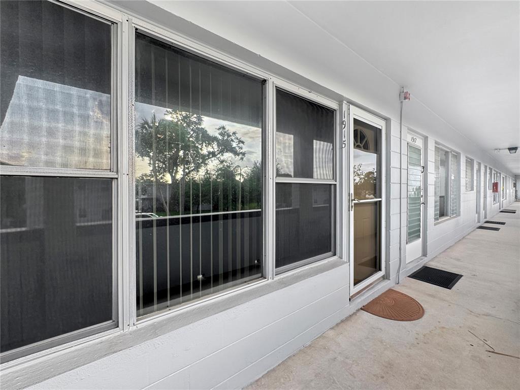 A concrete walkway leads to the entrance of a residential unit with large windows — 4300 58TH STREET N UNIT 1915, KENNETH CITY, FL