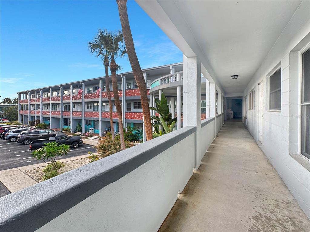 An outdoor concrete walkway overlooks a parking lot and a multi-story apartment building — 4300 58TH STREET N UNIT 1915, KENNETH CITY, FL
