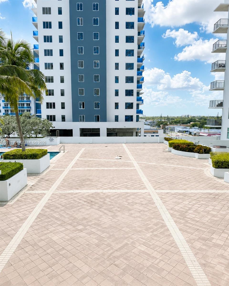 A paved outdoor terrace features planters, a swimming pool, and views of a high-rise building — 140 S Dixie Hwy # 510, Hollywood FL 33020, HOLLYWOOD, FL