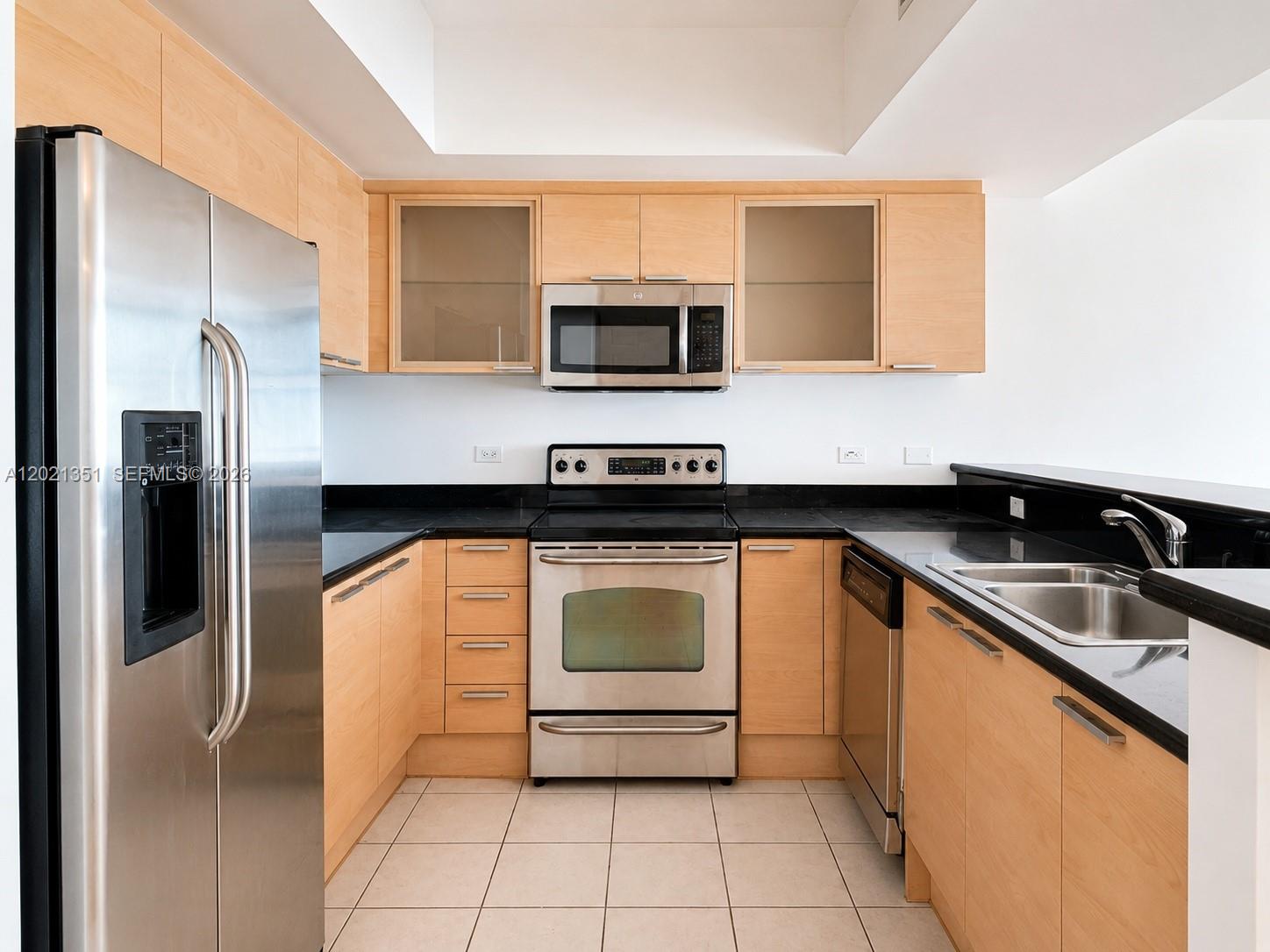 A kitchen features light wood cabinets, stainless steel appliances, and black countertops — 140 S Dixie Hwy # 510, Hollywood FL 33020, HOLLYWOOD, FL