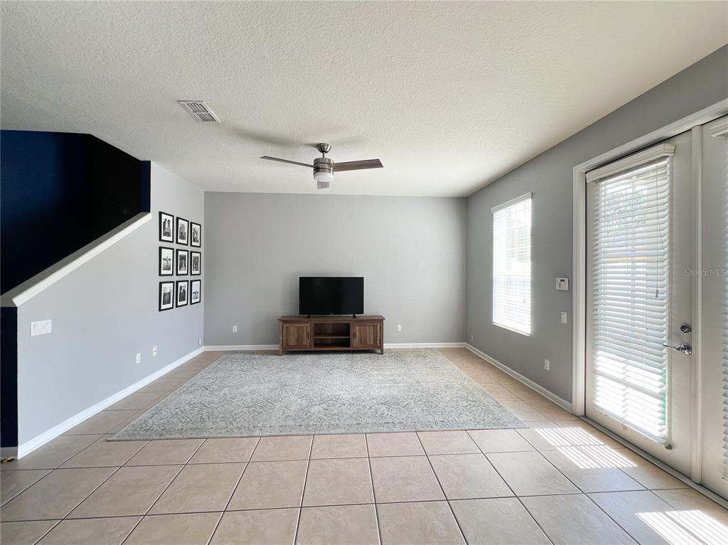 A living room with tile flooring, a ceiling fan, a television console, and a rug — 7722 FAIRGROVE AVENUE, WINDERMERE, FL