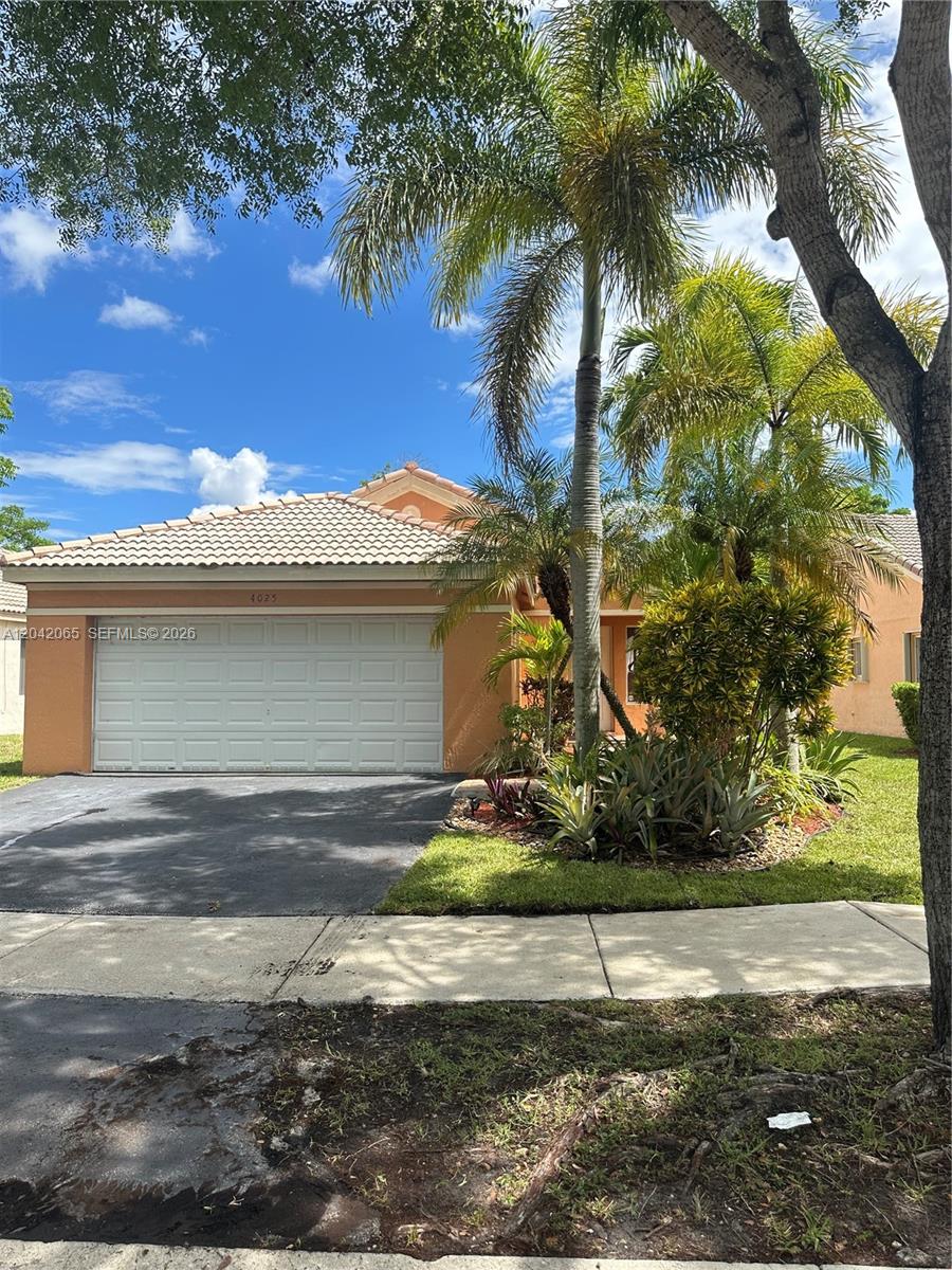 A single-story house with a white garage door, tan stucco walls, and palm trees — 4025 Pine Ridge Ln, Weston FL 33331, WESTON, FL