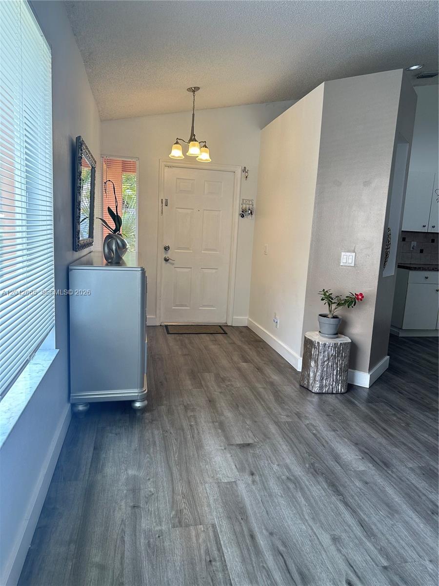 An entryway features gray wood-look flooring, a white front door, and a silver chest — 4025 Pine Ridge Ln, Weston FL 33331, WESTON, FL