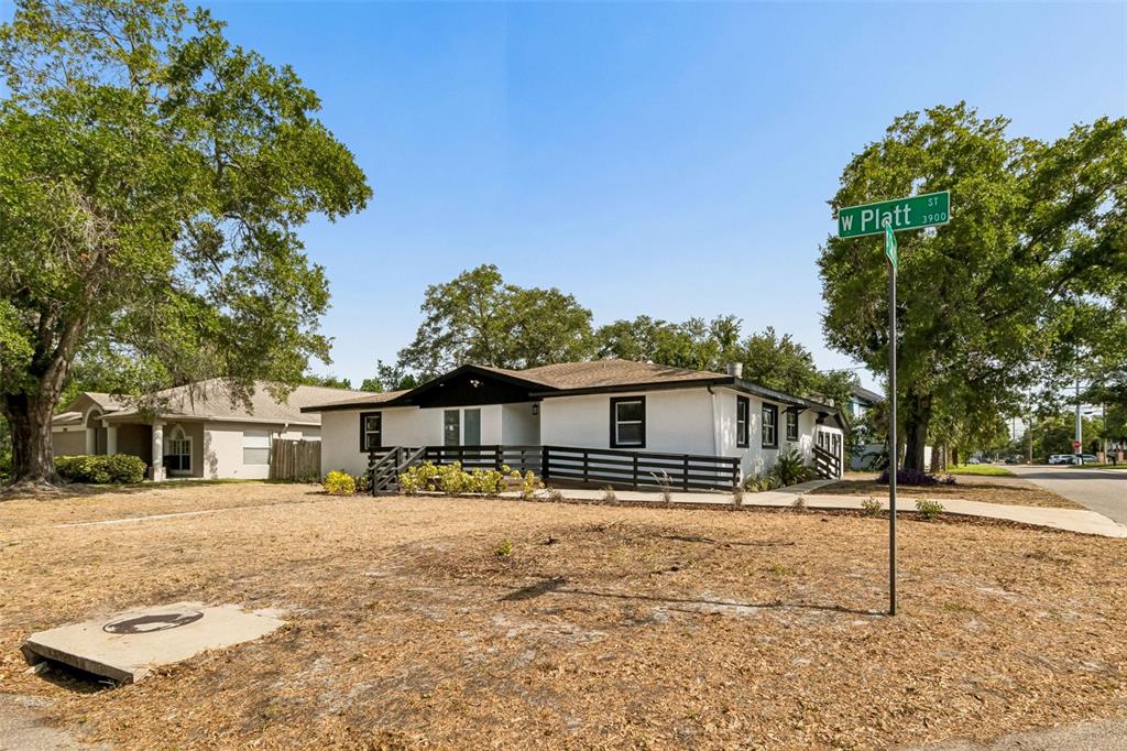A white single-story house with a black roof and porch railing sits on a corner lot — 3901 W PLATT STREET, TAMPA, FL