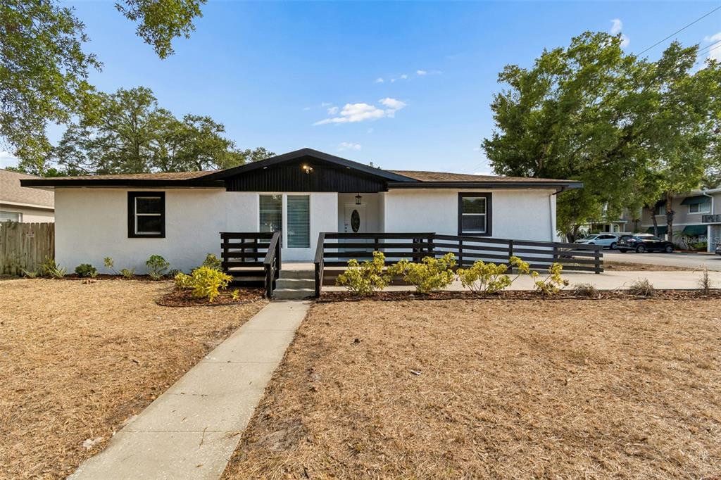 A single-story house with a white stucco exterior, black trim, and a wooden front deck — 3901 W PLATT STREET, TAMPA, FL