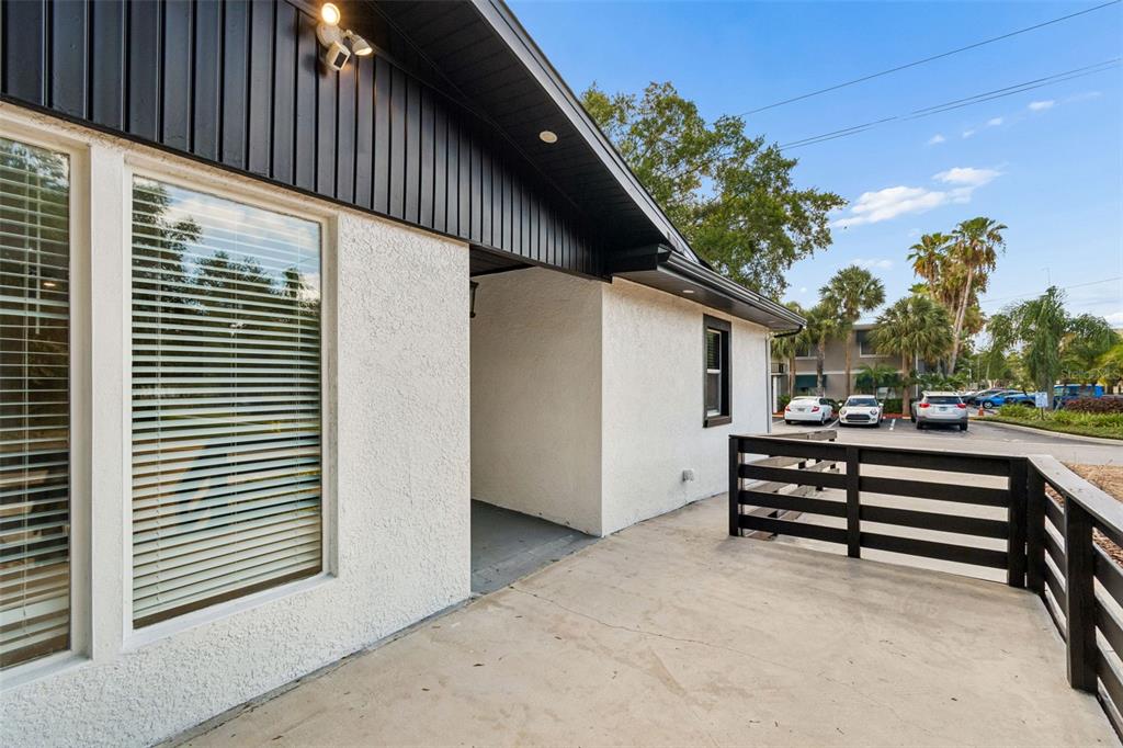 A concrete patio with a black wooden railing sits outside a white stucco building — 3901 W PLATT STREET, TAMPA, FL