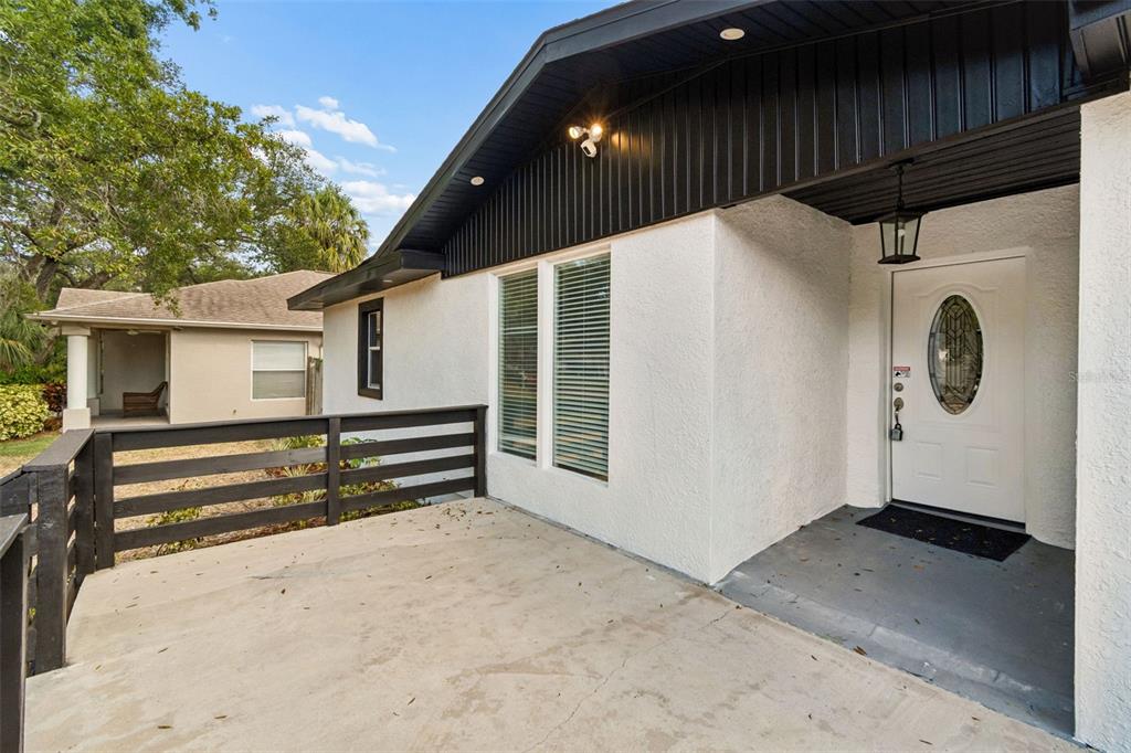 A white stucco house exterior features a black-railed concrete porch and a white front door — 3901 W PLATT STREET, TAMPA, FL