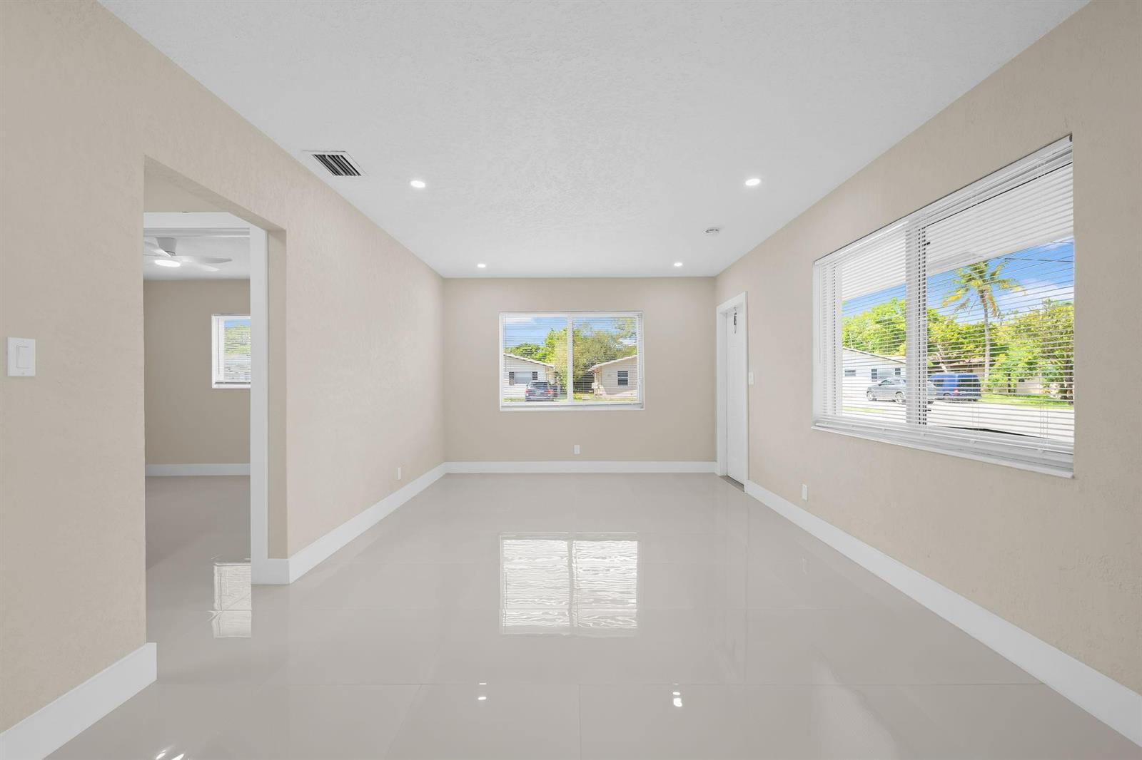 An empty room with beige walls, white tile flooring, and two windows with blinds — 832 NE 12th Avenue # 1, Pompano Beach FL 33060, POMPANO BEACH, FL