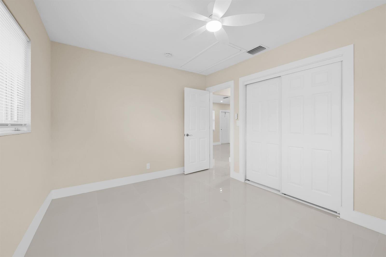 An empty bedroom features beige walls, white trim, tile flooring, a ceiling fan, and closets — 832 NE 12th Avenue # 1, Pompano Beach FL 33060, POMPANO BEACH, FL
