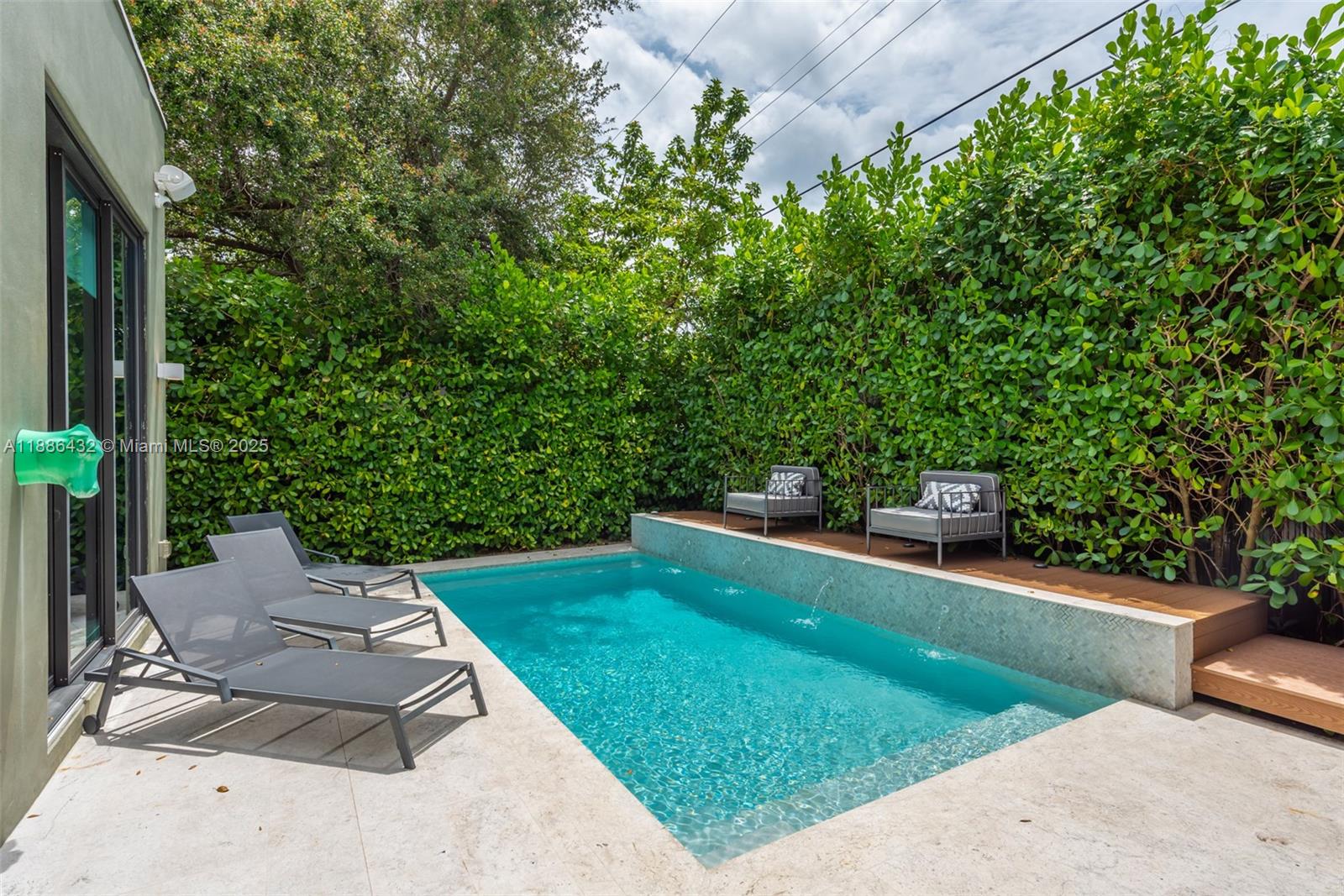 A rectangular swimming pool features a stone deck, lounge chairs, and a raised wooden platform — 4675 NE 2nd Ave, Miami FL 33137, MIAMI, FL