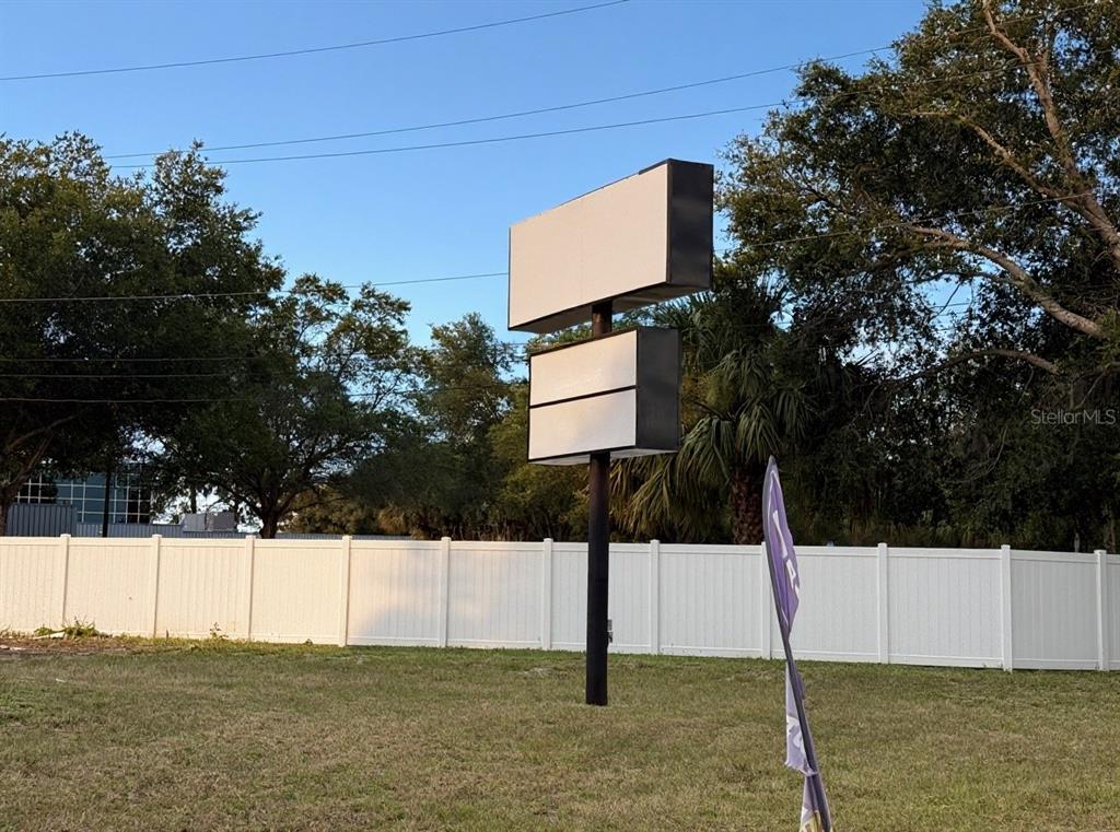 A tall, blank, double-sided sign stands in a grassy lot before a white privacy fence — 1424 N GULF AVENUE, CRYSTAL RIVER, FL