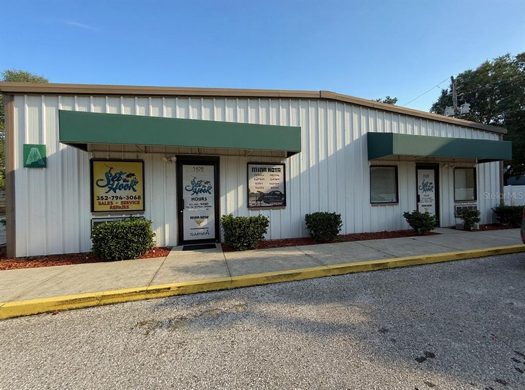 The exterior of a commercial building features white metal siding, green awnings, and two entrances — 1424 N GULF AVENUE, CRYSTAL RIVER, FL