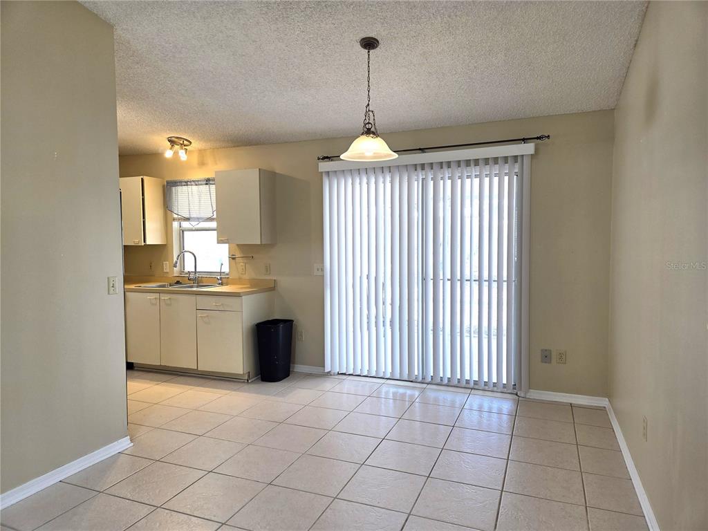 A kitchen and dining area with tile floors, beige walls, and sliding glass doors — 739 HEATHROW AVENUE, LADY LAKE, FL