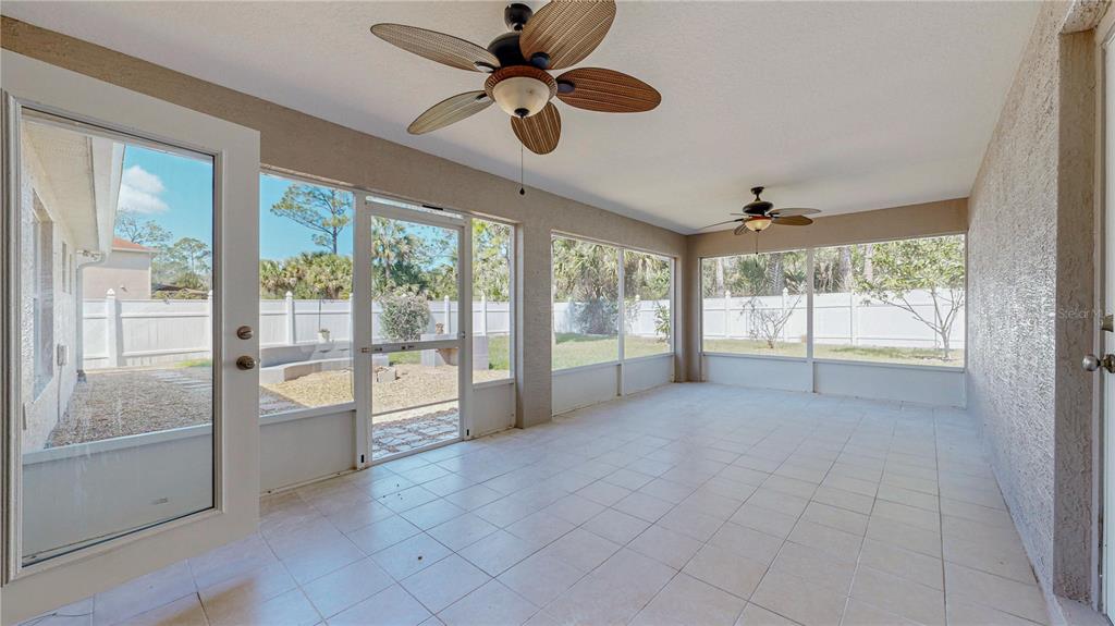 A tiled sunroom features two ceiling fans, large screen windows, and a door to the yard — 7 SMOKEHOUSE PLACE, PALM COAST, FL