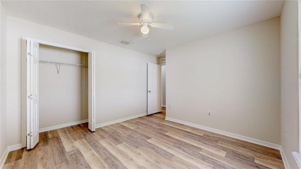 A bedroom with light-colored walls, wood-look flooring, a ceiling fan, and an open closet — 7 SMOKEHOUSE PLACE, PALM COAST, FL
