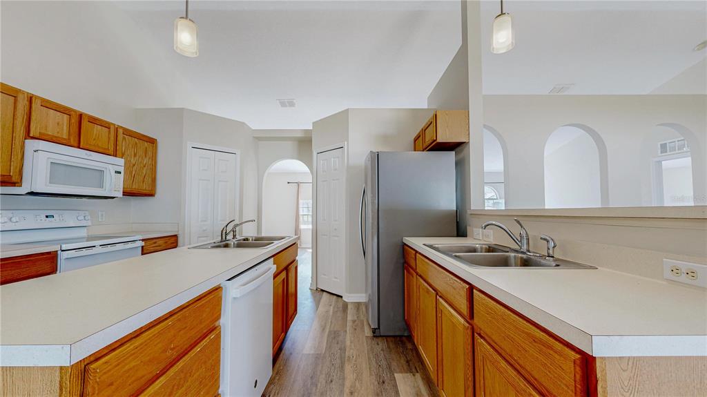 A kitchen features wood cabinets, white countertops, stainless steel appliances, and a double sink — 7 SMOKEHOUSE PLACE, PALM COAST, FL