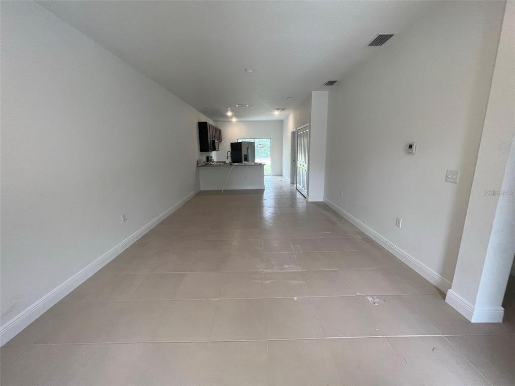 An open-concept living area features light-colored tile flooring and a view toward a kitchen — 16170 SW 33RD AVENUE ROAD, OCALA, FL
