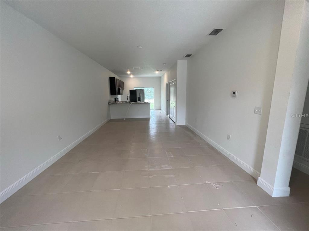An open-concept living area features light tile flooring, white walls, and a distant kitchen — 16170 SW 33RD AVENUE ROAD, OCALA, FL