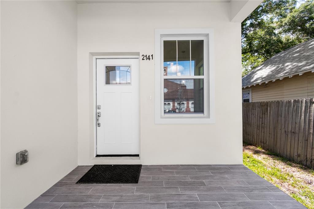 A covered porch features gray tile flooring, a white front door, and a single window — 2141 UPTON COURT S, ST PETERSBURG, FL