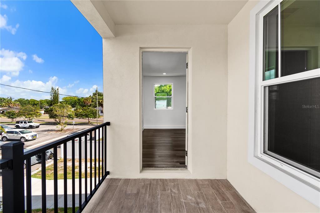 A covered balcony with wood-look tile flooring overlooks a parking lot and street — 2141 UPTON COURT S, ST PETERSBURG, FL
