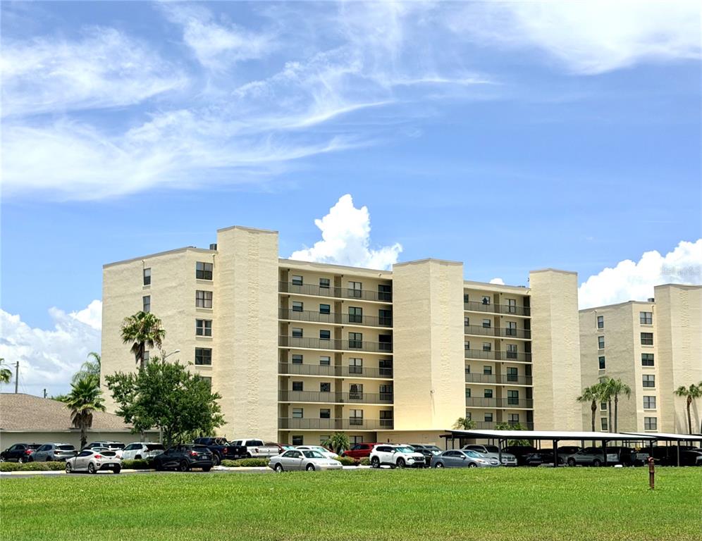 A multi-story apartment building with balconies and a parking lot in front — 1000 COVE CAY DRIVE UNIT 4D, CLEARWATER, FL