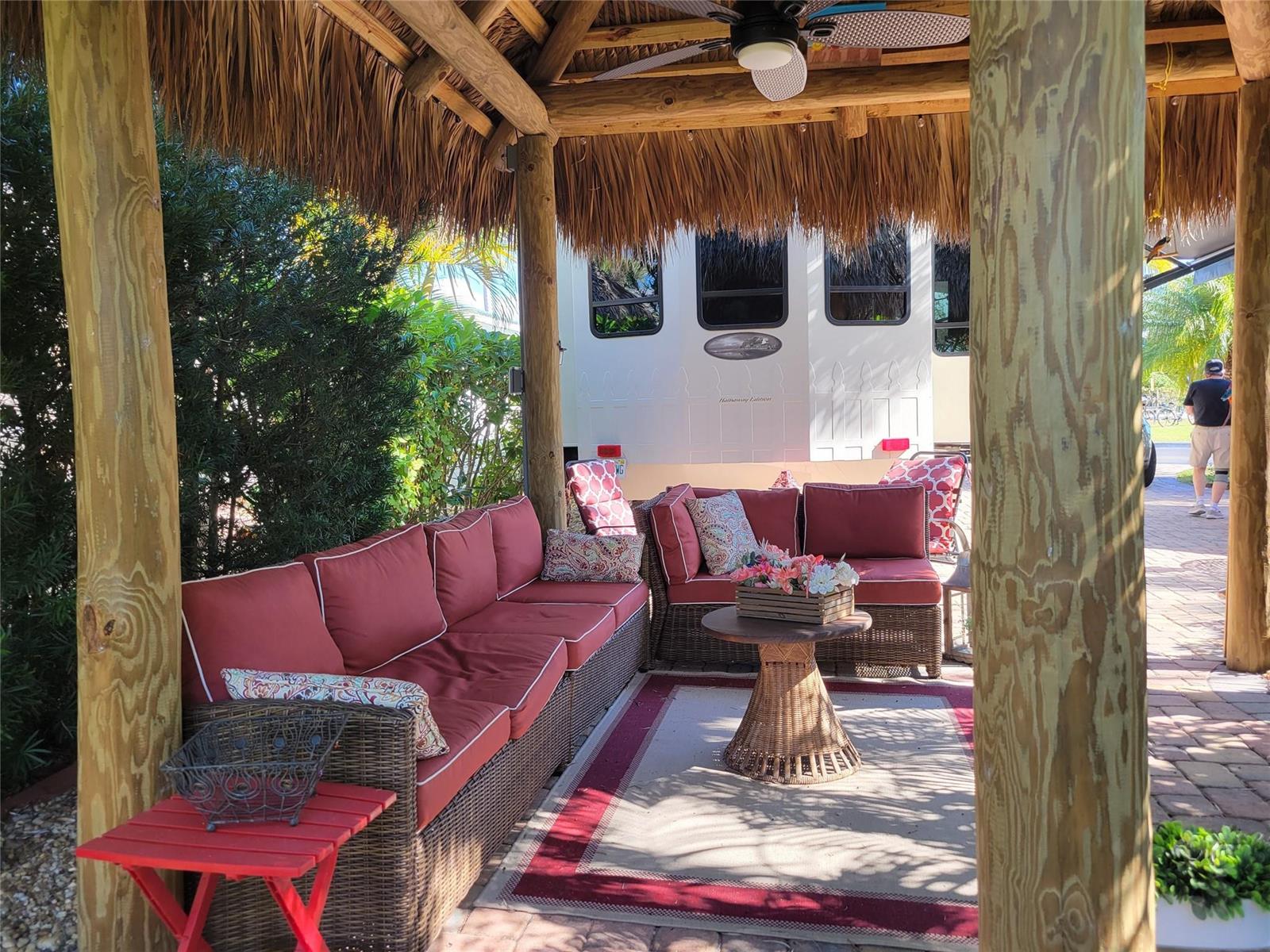 A covered outdoor patio features wicker sectional seating with red cushions under a thatched roof — 3755 SE 6th Glen, Okeechobee FL 34974, OKEECHOBEE, FL