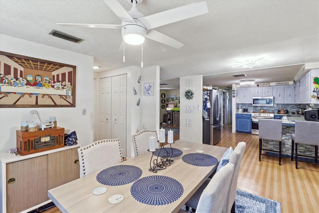 A dining area with a table and chairs opens into a kitchen with blue cabinets — 1149 N TRUDEL POINT, CRYSTAL RIVER, FL