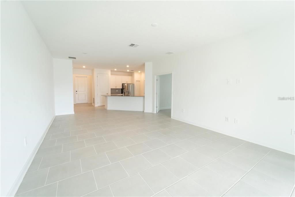 An open-concept living area features white walls, light gray tile flooring, and a kitchen island — 4032 REDBRIDGE LOOP, DAVENPORT, FL
