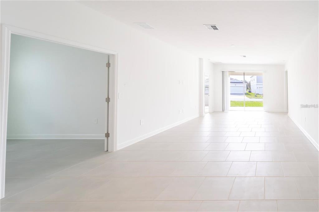 An interior view of a bright, open-concept living area with white walls and tile flooring — 4032 REDBRIDGE LOOP, DAVENPORT, FL