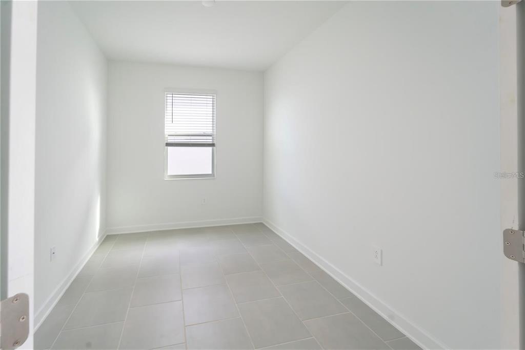An empty room with white walls, gray tile flooring, and a single window with blinds — 4032 REDBRIDGE LOOP, DAVENPORT, FL