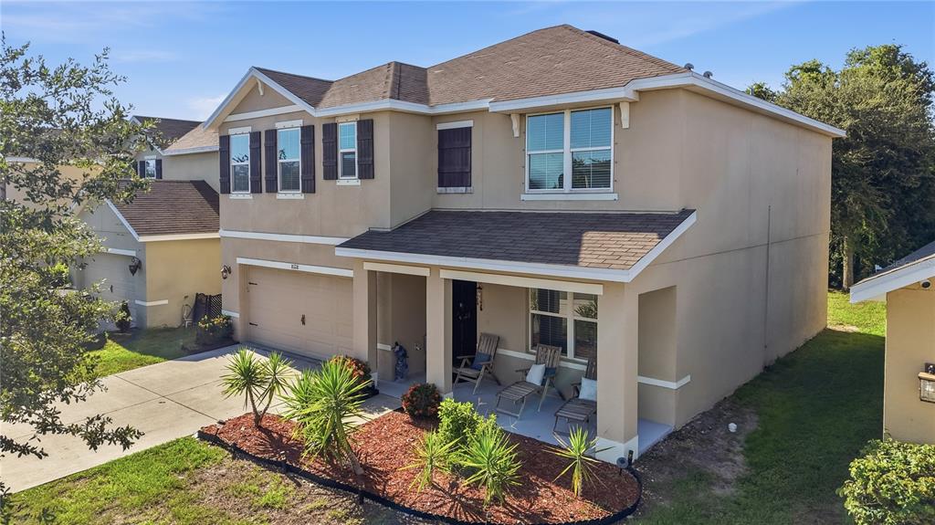 An exterior view of a two-story tan house with a garage and a front porch — 8128 HARWICH PORT LANE, GIBSONTON, FL